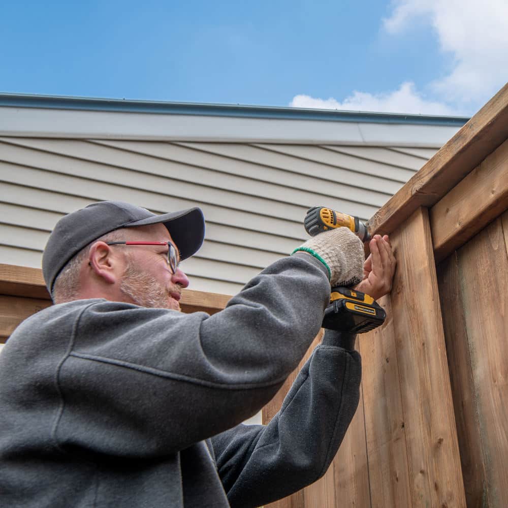 Fence contractor building a wooden fence.